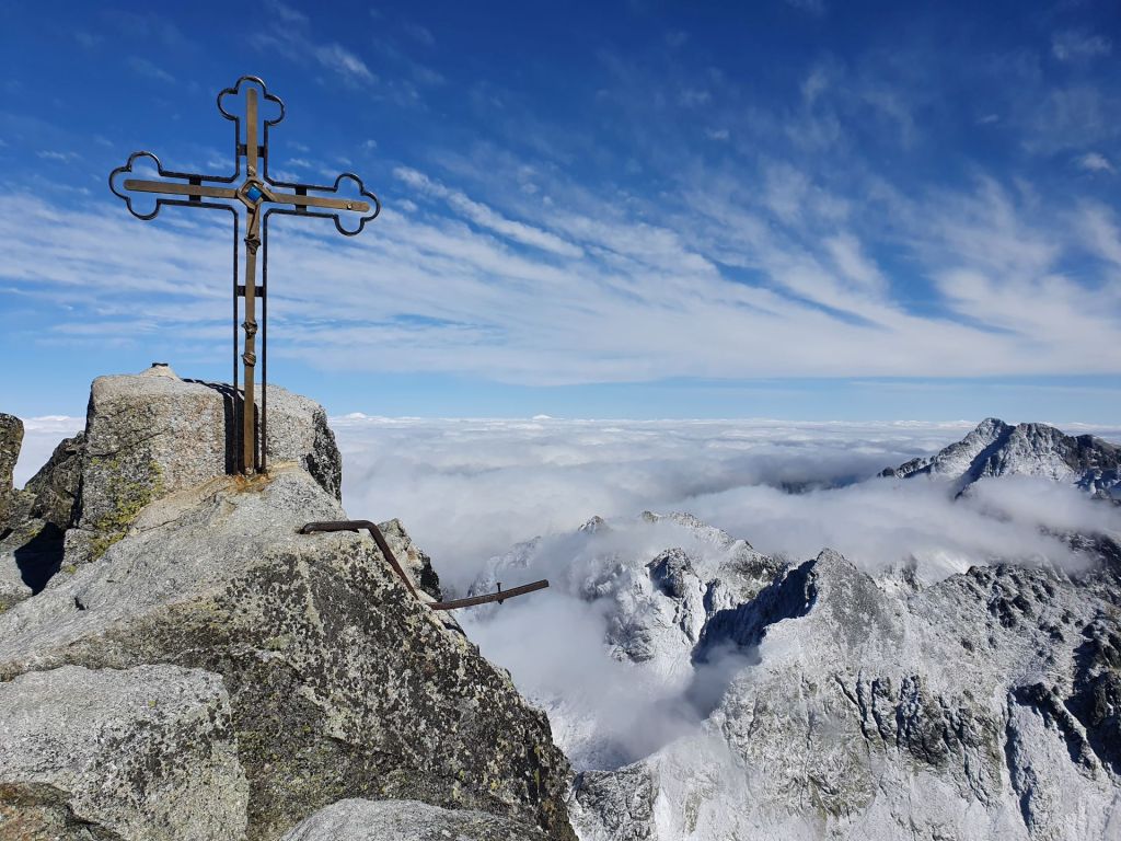 Summit cross on Gerlachovský štít, Slovakia, with clouds and peaks in the background.